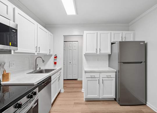 A kitchen with white cabinets and a black fridge.