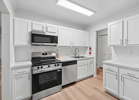 A modern kitchen with white cabinets and stainless steel appliances.