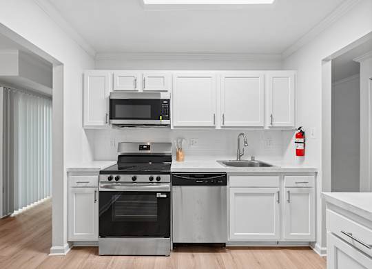 A modern kitchen with white cabinets and stainless steel appliances.