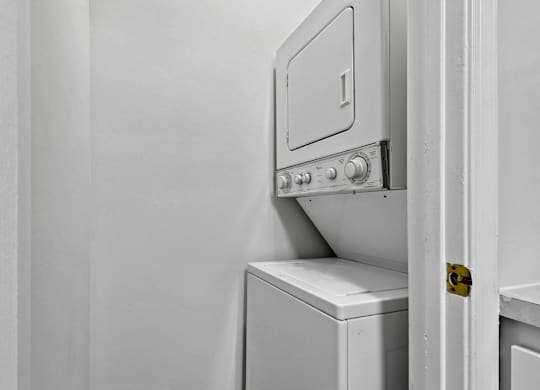 Stacked washer and dryer unit in laundry closet at The Courts at Fair Oaks Apartments, Fairfax, VA 22030