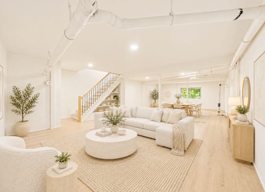 A white living room with a staircase in the background.