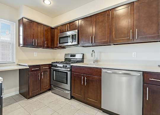 A kitchen with brown cabinets and stainless steel appliances. at Chatham Hill, New Jersey, 07928