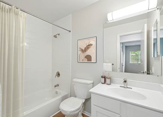 A white bathroom with a toilet, sink, and shower.