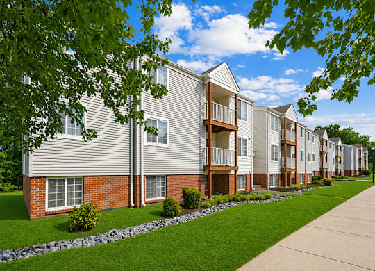 Apartment building with a sidewalk and greenery.