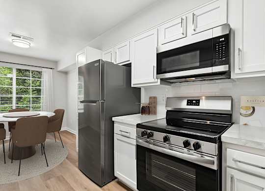 A kitchen with a black fridge, stove, and microwave.
