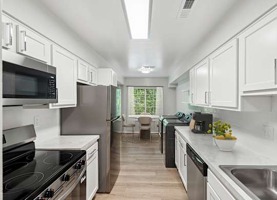 A modern kitchen with white cabinets and stainless steel appliances.