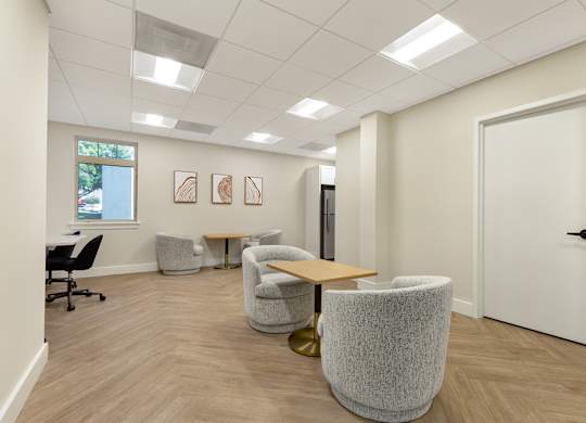 a waiting room with chairs and a table in front of a door at Copper and Quarry Village, Pikesville, 21209