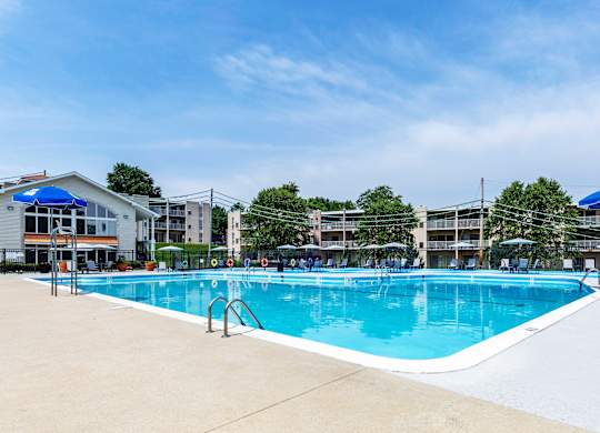 a swimming pool with umbrellas and buildings in the background at Copper and Quarry Village, Pikesville