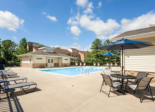 Outdoor swimming pool with lounge chairs and umbrellas at The at Elmwood Terrace Apartments, Frederick, MD