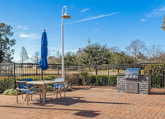 A patio with a table, chairs, and an umbrella. at Greenbrier Estates, Slidell, 70460