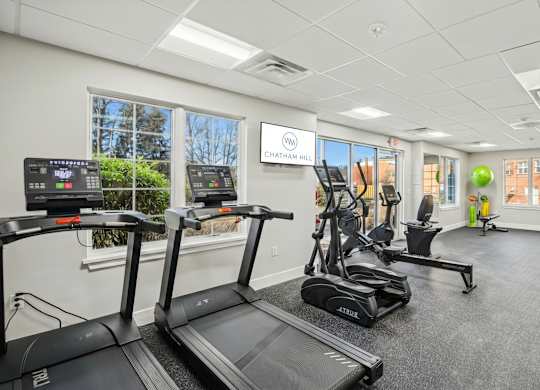 A gym with treadmills, elliptical machines, and other exercise equipment.