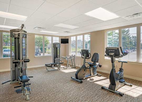 A gym with a variety of equipment including a treadmill, elliptical machines, and a weight machine. at The Apartments at Hunters Glen, Frederick, MD