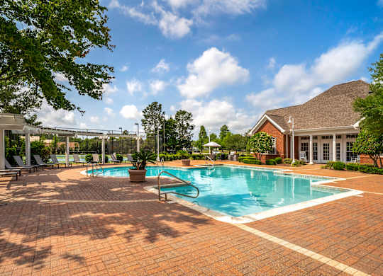 A large outdoor swimming pool surrounded by a brick patio.