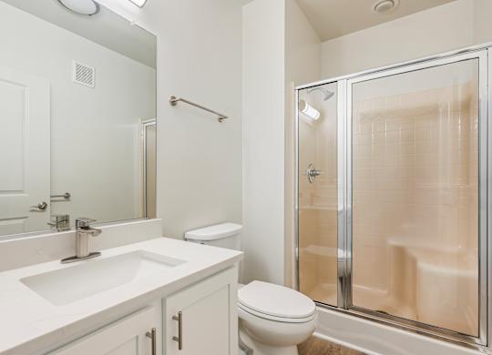 A white bathroom with a sink, toilet, and shower. at River House Apartments, Norfolk