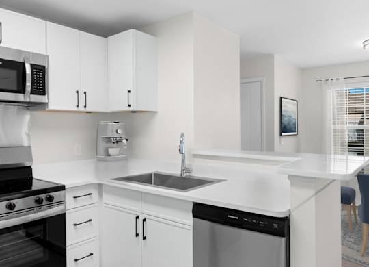 A modern kitchen with white cabinets and appliances. at Reflection Pointe, Flowood, Mississippi