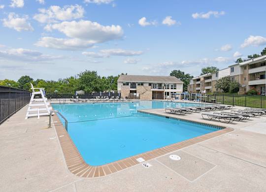 A large outdoor swimming pool with a white ladder and a black fence.