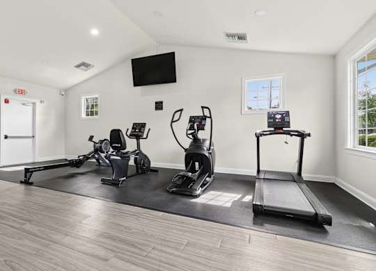 A spacious home gym with a treadmill, rowing machine, and stationary bike.