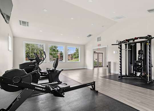 A home gym with a rowing machine and a squat rack.