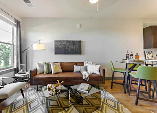 a living room and dining room with a couch and chairs and a table with a chair  at The Addison, Baton Rouge, LA