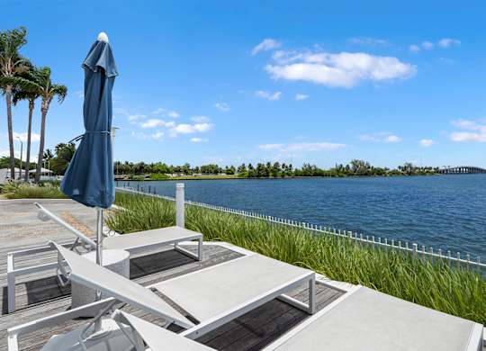 Waterfront lounge chairs with blue umbrella and lake view at The Hamilton Apartments, Florida