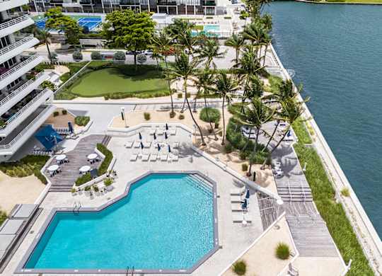 Waterfront pool deck with palm trees and lounge chairs at The Hamilton Apartments, Miami, 33137