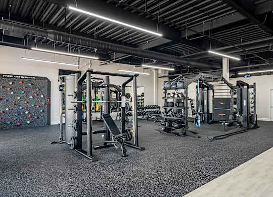 a gym with weights machines and a rock wall at Villaggio Apartments, Bossier City, LA
