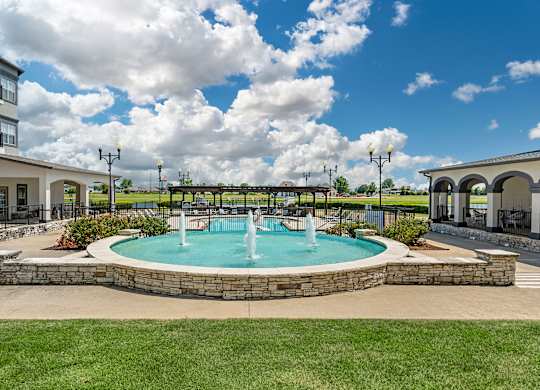 a fountain in the middle of a pool in front of a building at Villaggio Apartments, Bossier City, LA