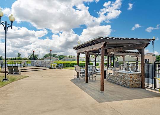 an outdoor patio with tables and chairs and a pergola at Villaggio Apartments, Bossier City