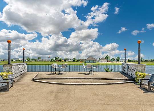 a patio with tables and chairs overlooking a body of water at Villaggio Apartments, Louisiana