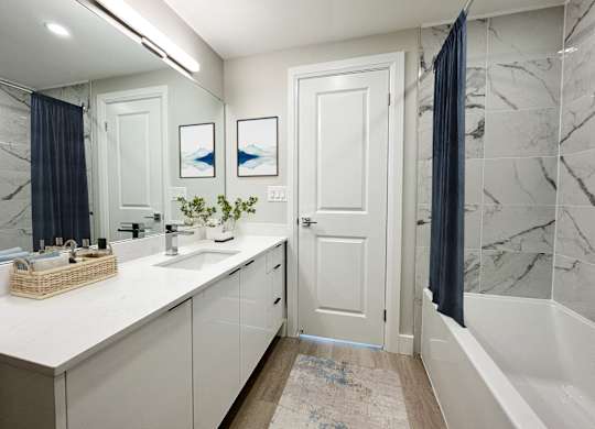 a white and gray bathroom with a shower and a sink