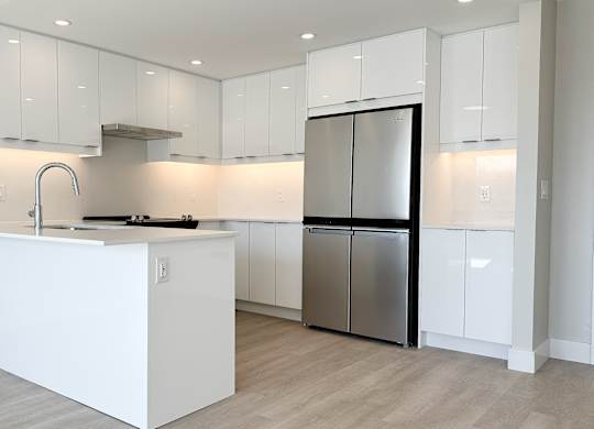a kitchen with white cabinets and a stainless steel refrigerator