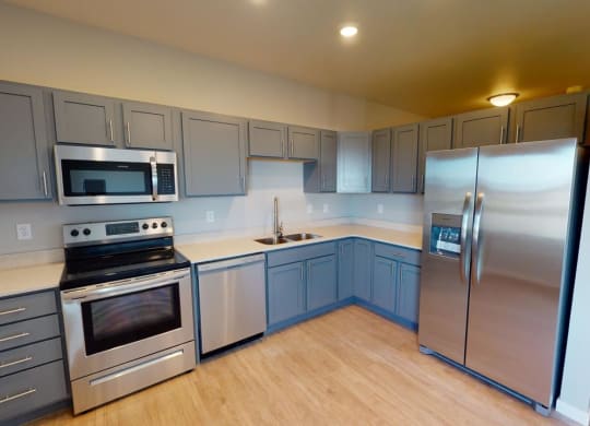 a kitchen with stainless steel appliances and blue cabinets at Northern Lights a Lifestyle-Driven Community, West Fargo, ND, 58078
