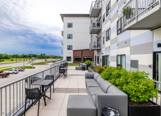the terrace of a building with tables and chairs and a balconyat Northern Lights a Lifestyle-Driven Community, West Fargo, 58078