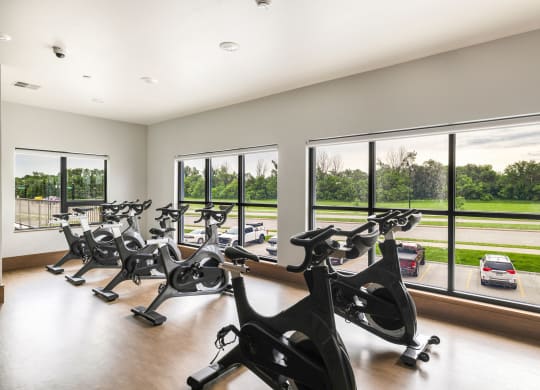 a gym with a row of exercise bikes in front of windows at Northern Lights a Lifestyle-Driven Community, West Fargo, 58078