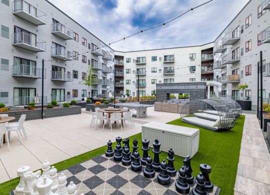 an apartment patio with tables and chairs and a large chess setat Northern Lights a Lifestyle-Driven Community, West Fargo, North Dakota
