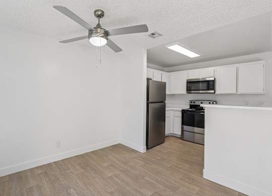 A kitchen with a refrigerator, microwave, and oven.