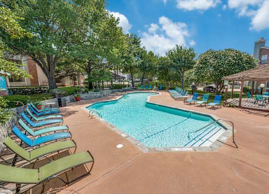 a resort style swimming pool with lounge chairs and umbrellas at Foxborough Apartments, Irving, TX, Texas, 75061