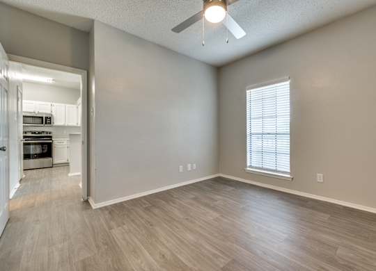 an empty living room with a ceiling fan and a kitchen at Foxborough Apartments, Irving, TX, Texas, 75061