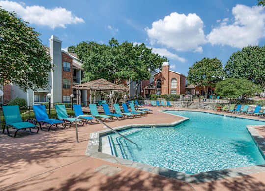 a resort style swimming pool with blue chairs and a building in the background at Foxborough Apartments, Irving, TX, Texas, 75061