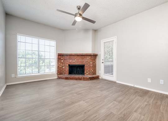 an empty living room with a fireplace and a ceiling fan at Foxborough Apartments, Irving, TX, Texas, 75061