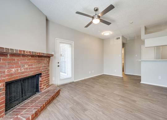 an empty living room with a brick fireplace and a ceiling fan at Foxborough Apartments, Irving, TX, Texas, 75061