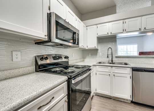 an empty kitchen with white cabinets and a stove and microwave at Foxborough Apartments, Irving, TX, Texas, 75061