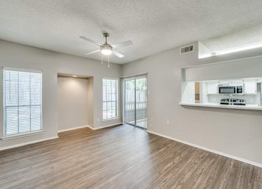 an empty living room with a ceiling fan and a kitchen at Foxborough Apartments, Irving, TX, Texas, 75061