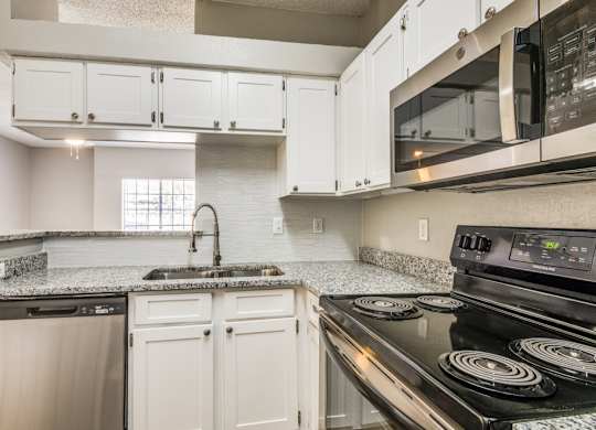 a kitchen with white cabinets and black appliances at Foxborough Apartments, Irving, TX, 75061