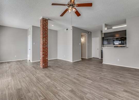 an empty living room with a ceiling fan and a kitchen at Foxborough Apartments, Irving, TX, Texas, 75061