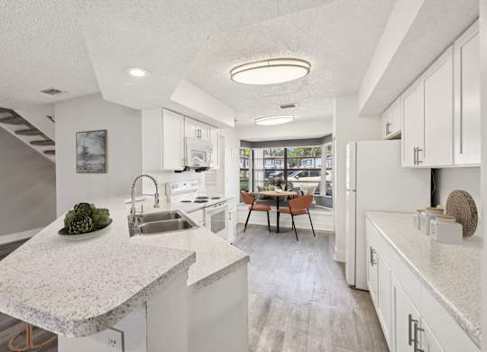 A modern kitchen with a marble countertop and a dining table with chairs.