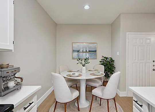 A dining room with a white table and chairs.