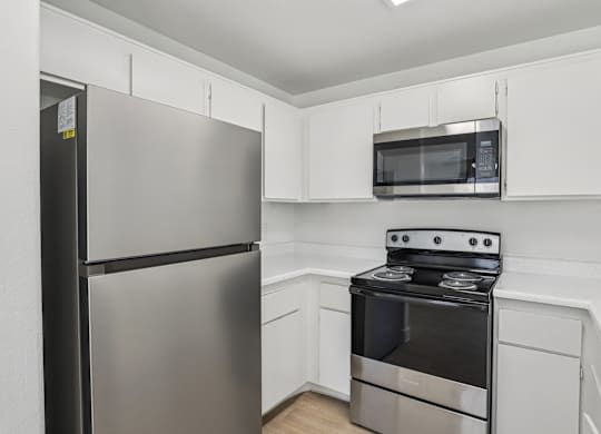 A kitchen with a stainless steel refrigerator, microwave, and oven.