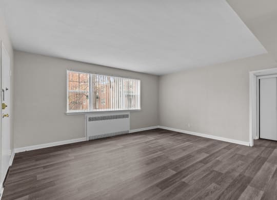 the living room of an apartment with wood flooring and a window