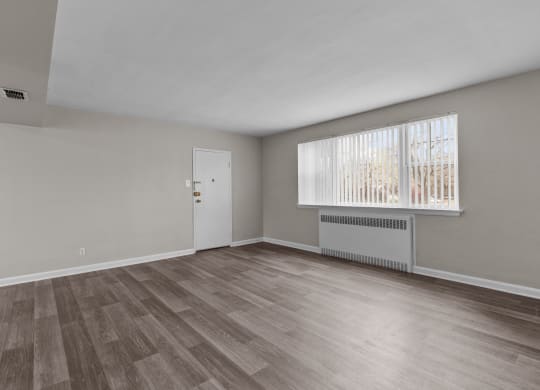 the living room of an empty house with wood flooring and a window